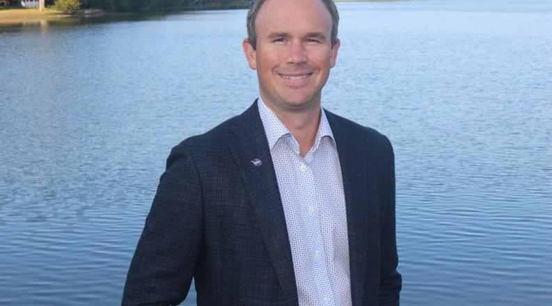 A man stands near a lake